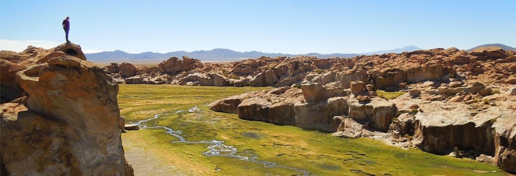 Wide landscape photo of a travel photographer in mountain landscape