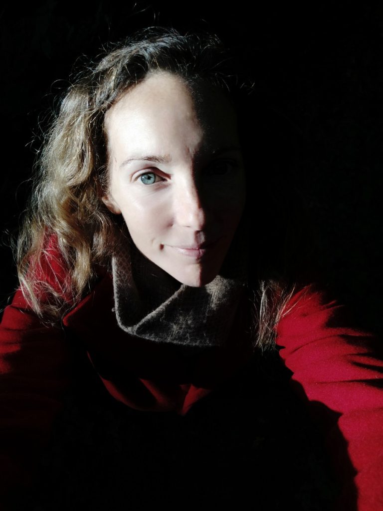 A picture of a woman in a red coat with shadows around her in portrait style.